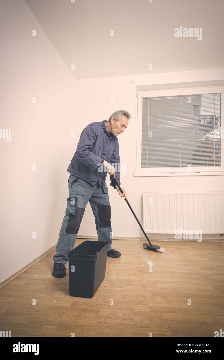 Older man cleaning and repairing floor in empty apartment Stock Photo ...