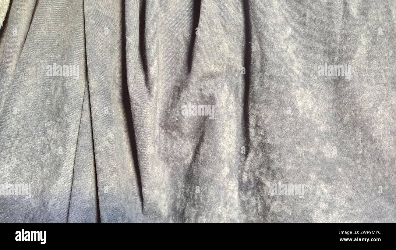 Close-up of velvet thick fabric for curtains. Blue-gray color. The material hangs in waves. Sample for home decoration. Corduroy piece of fabric. Stock Photo