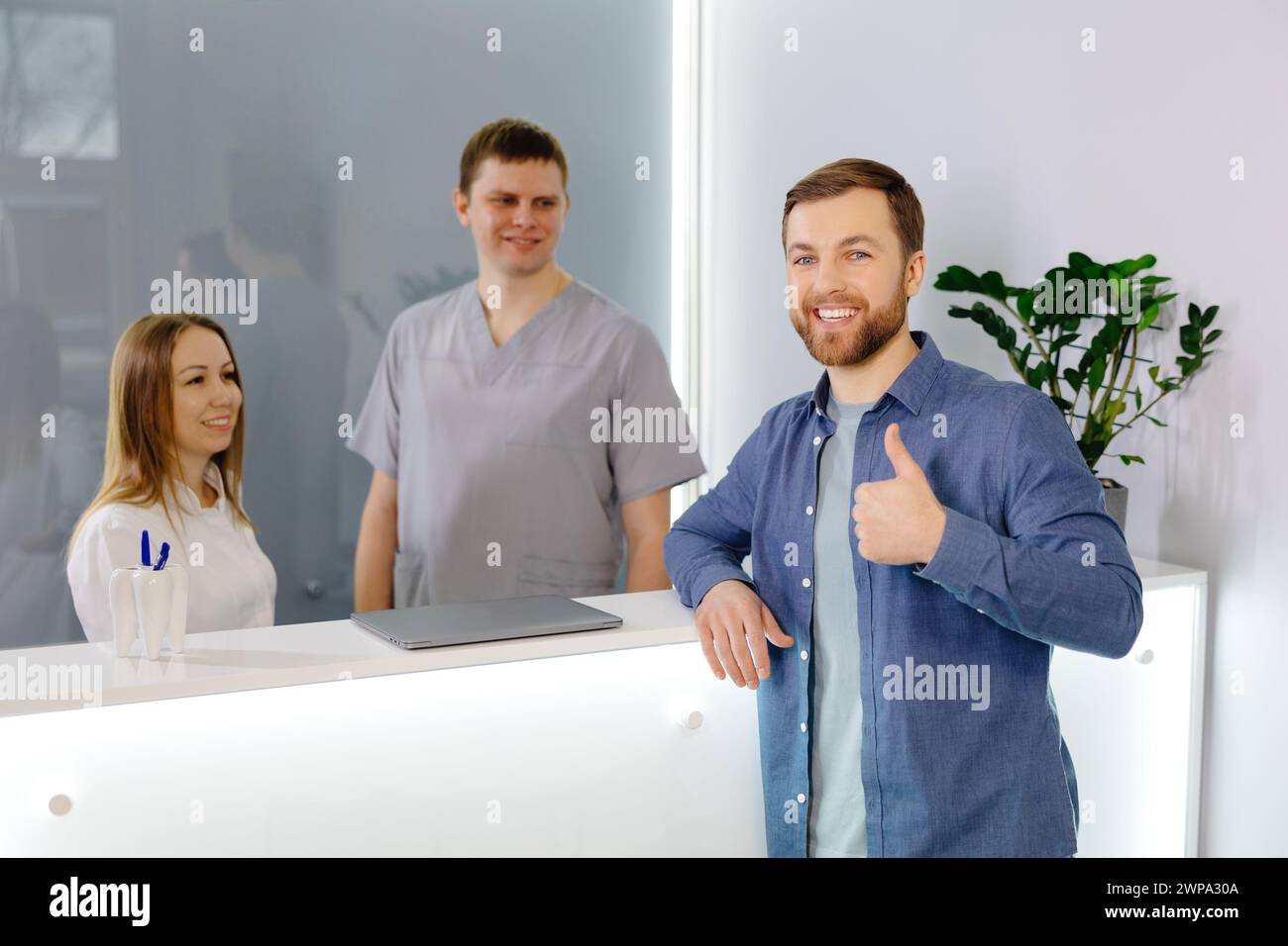 Grateful patient. Man standing at the reception of dental clinic and very pleased for the treatment Stock Photo