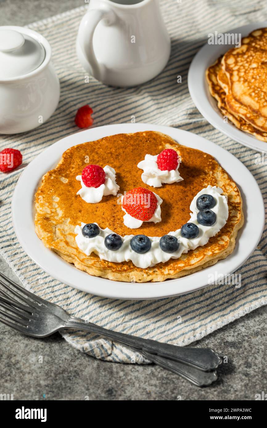 Sweet American Smiley Face Breakfast Pancakes with Whipped Cream and Berries Stock Photo