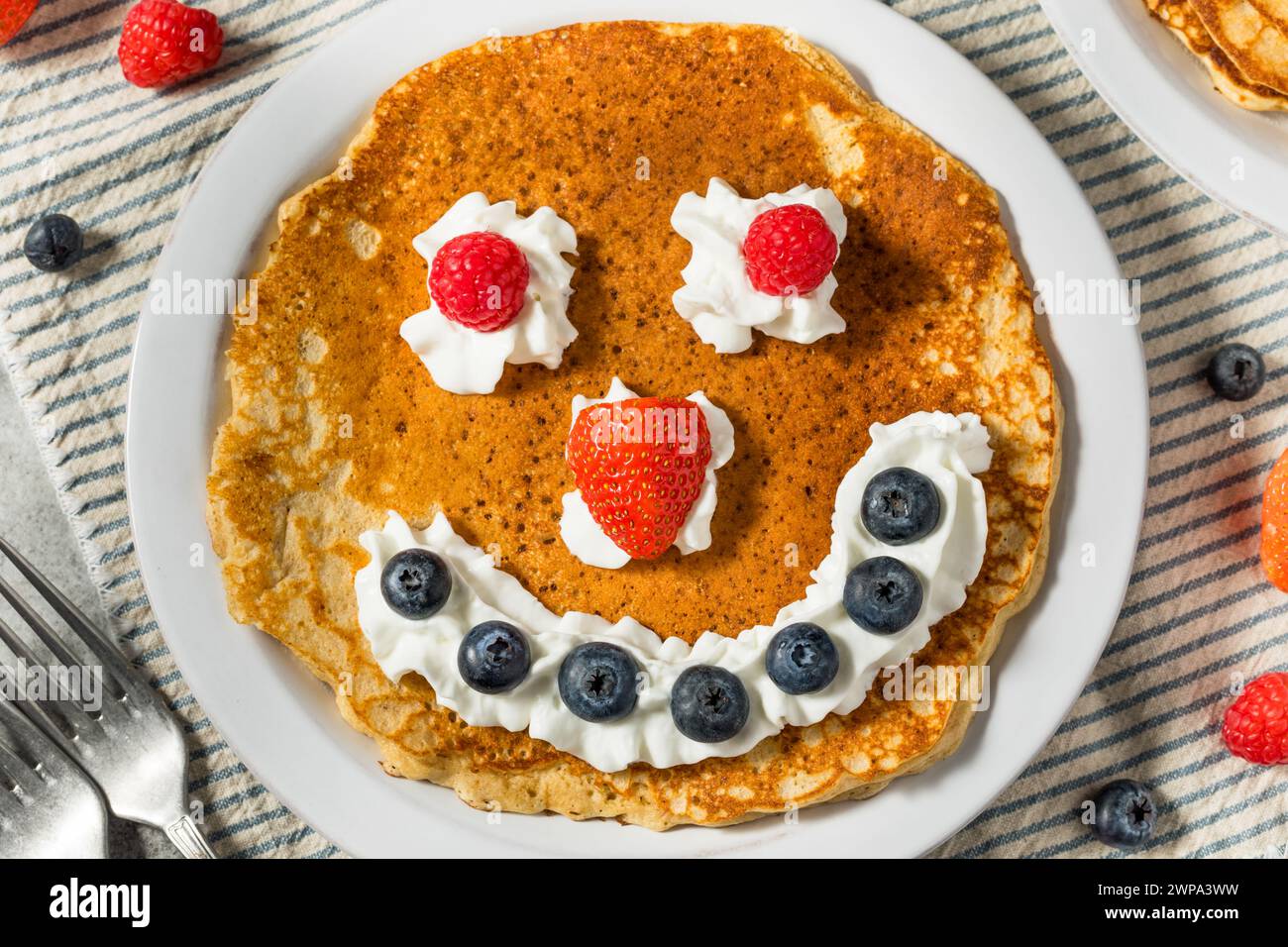 Sweet American Smiley Face Breakfast Pancakes with Whipped Cream and Berries Stock Photo