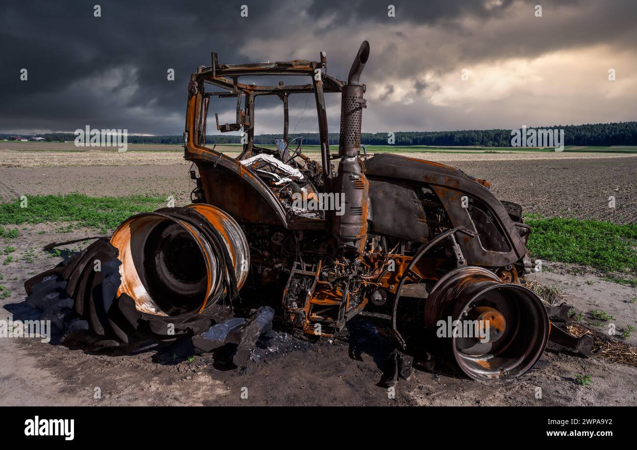 Fully destroyed burnt down tractor on a field Stock Photo