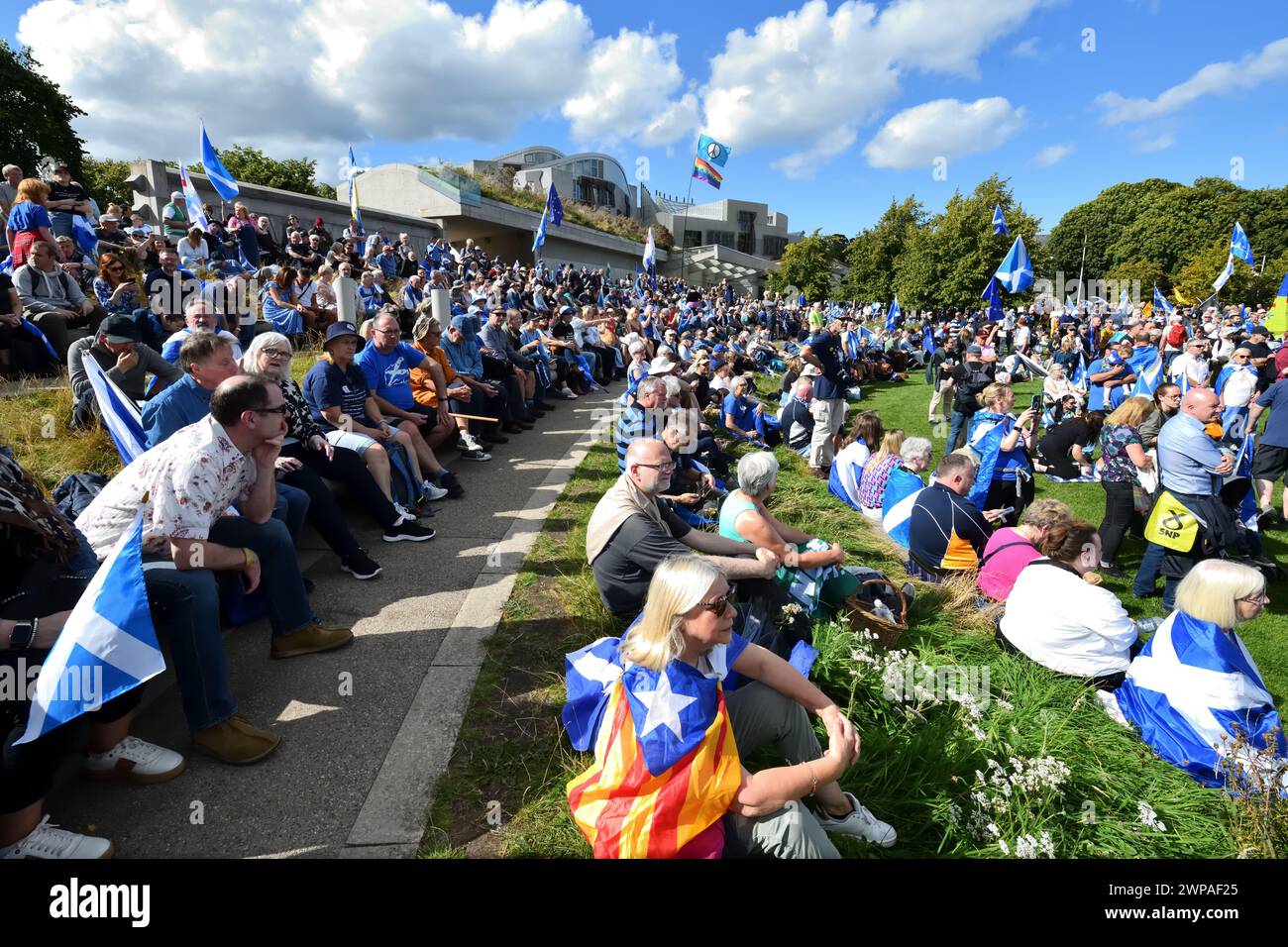 A large Scottish crowd sitting in the sun at Holyrood parliament Edinburgh, after a  peaceful 'Believe in Scotland' march for independence.. Stock Photo