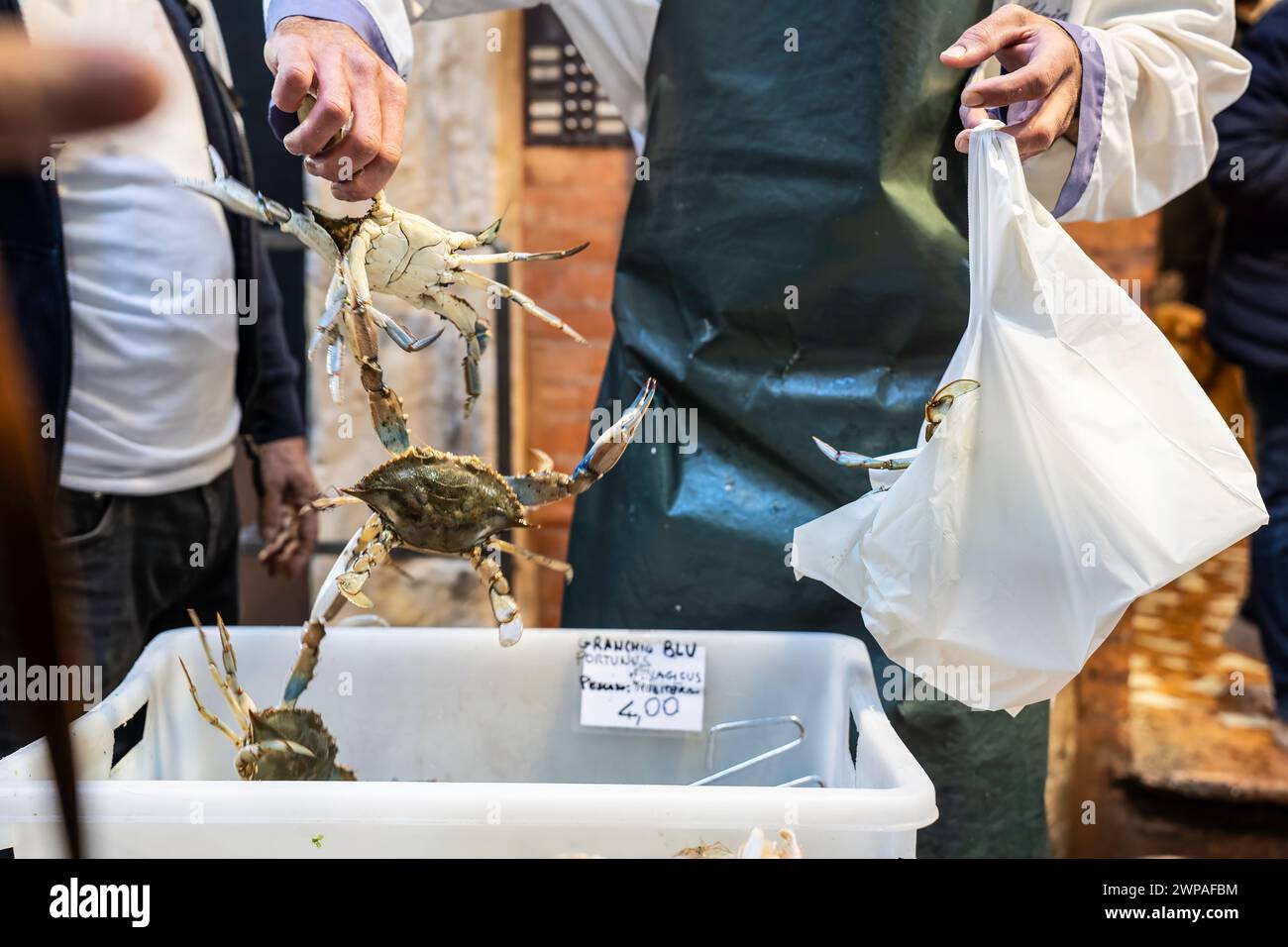 People at the market to fish counter - The seller is putting callinectes sapidus blue crabs into the bag - blue crabs are american atlantic coasts - T Stock Photo