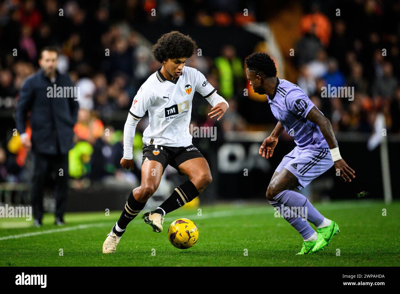 Valencia CF's Spanish-Dominican player Peter Federico trying to dribble past Real Madrid Vinicius with coach Ruben Baraja looking on in the background Stock Photo