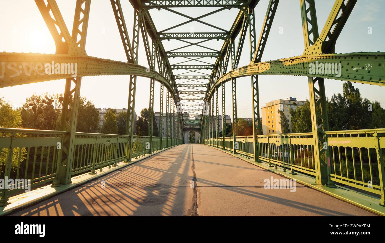 morning sun over pedestrian bridge with green riveted iron beams. Döblinger Steg - footbridge in art nouveau style that crosses Danube canal. Stock Photo