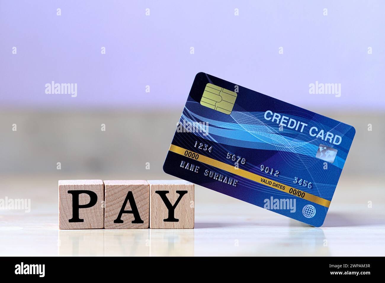 Blue credit card and wood cube letter put on wooden table with spending via credit card Instead of cash concept Stock Photo
