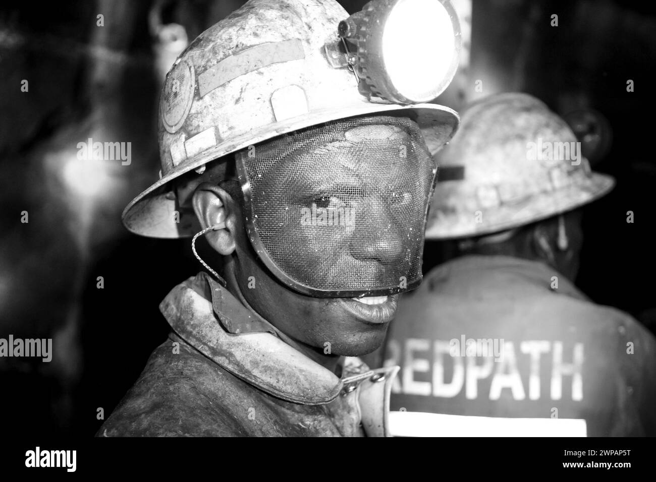 A coal miner wearing safety gear in dim light Stock Photo