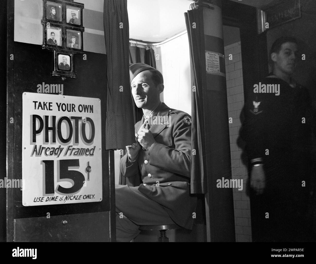 Man in military uniform sitting in  picture-taking machine in lobby at United Nations service center, Washington, D.C., USA, Esther Bubley, U.S. Office of War Information, December 1943 Stock Photo