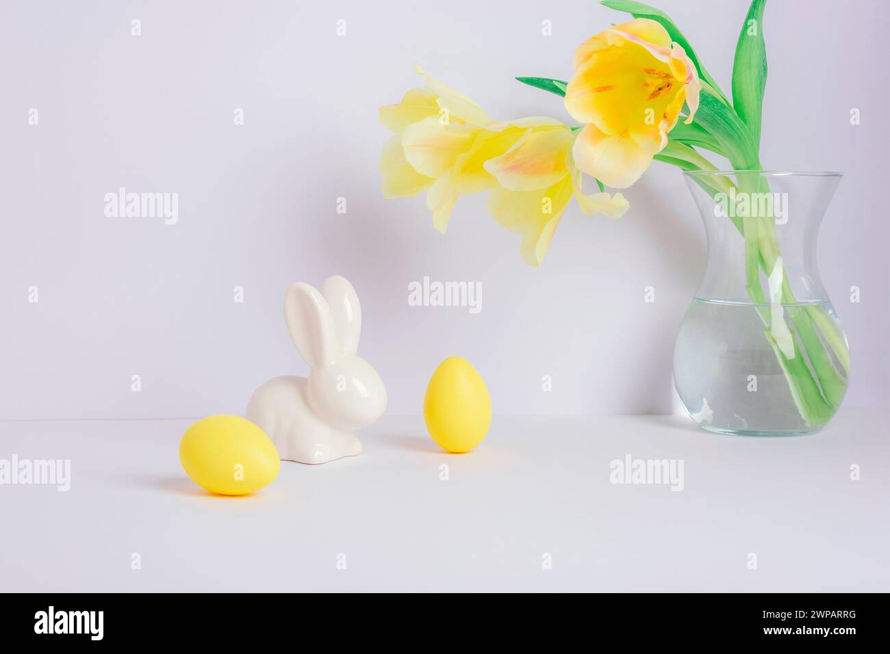 Yellow tulips in vase and Easter decorations on white background. Easter concept. Stock Photo