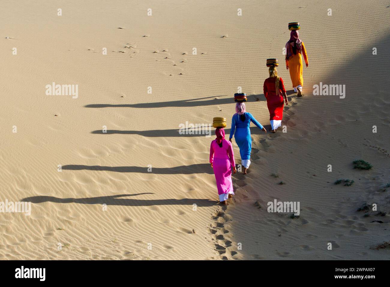 Women carrying baskets, walking in the sand dunes near Phan Rang, central Vietnam Stock Photo