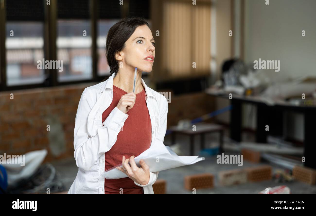 Interested brunette making notes while planning home renovation Stock Photo