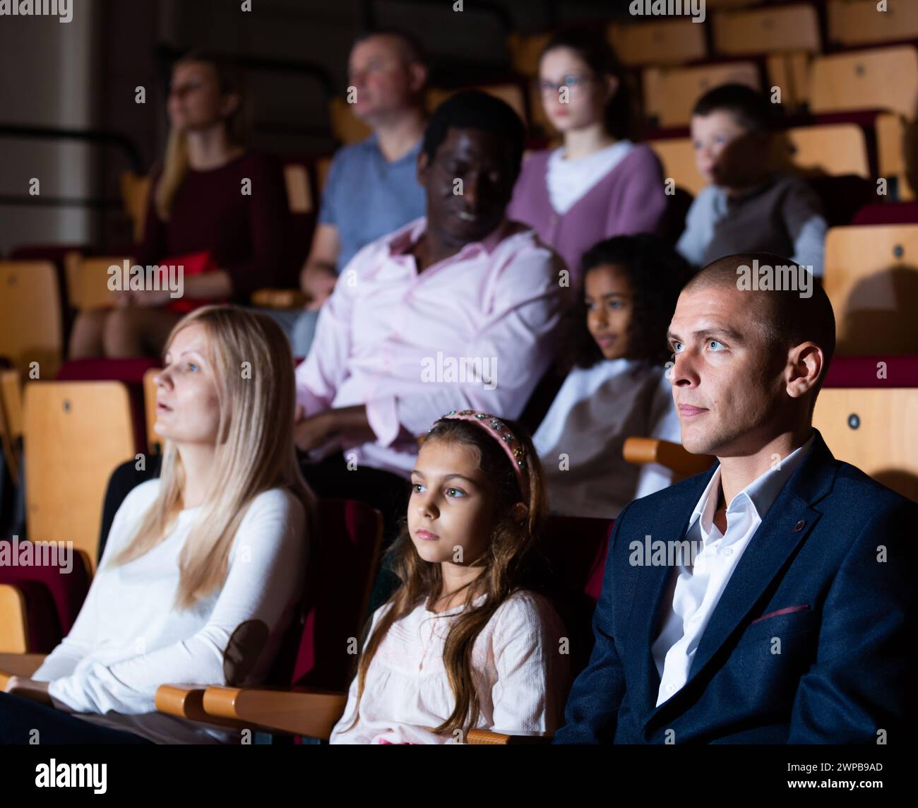 Family of theatergoers with tween daughter watching performance in ...