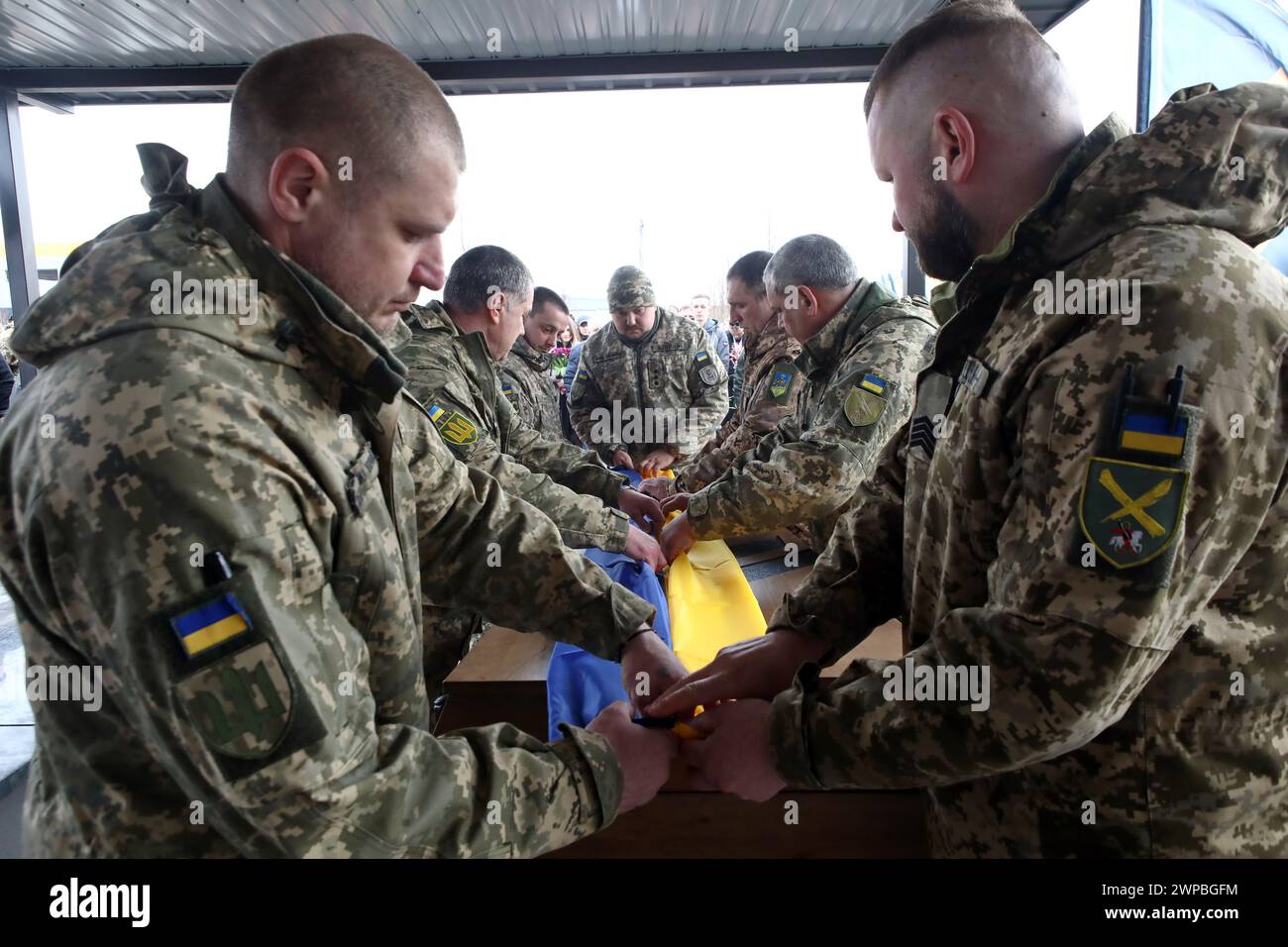 Non Exclusive: BUCHA, UKRAINE - MARCH 5, 2024 - Servicemen cover the coffin with a national flag during the memorial service for Ukrainian defender Da Stock Photo