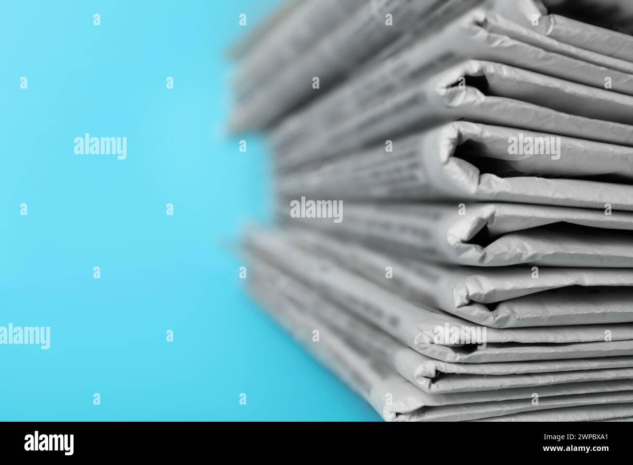 Stack of newspapers on light blue background, closeup. Journalist's work Stock Photo