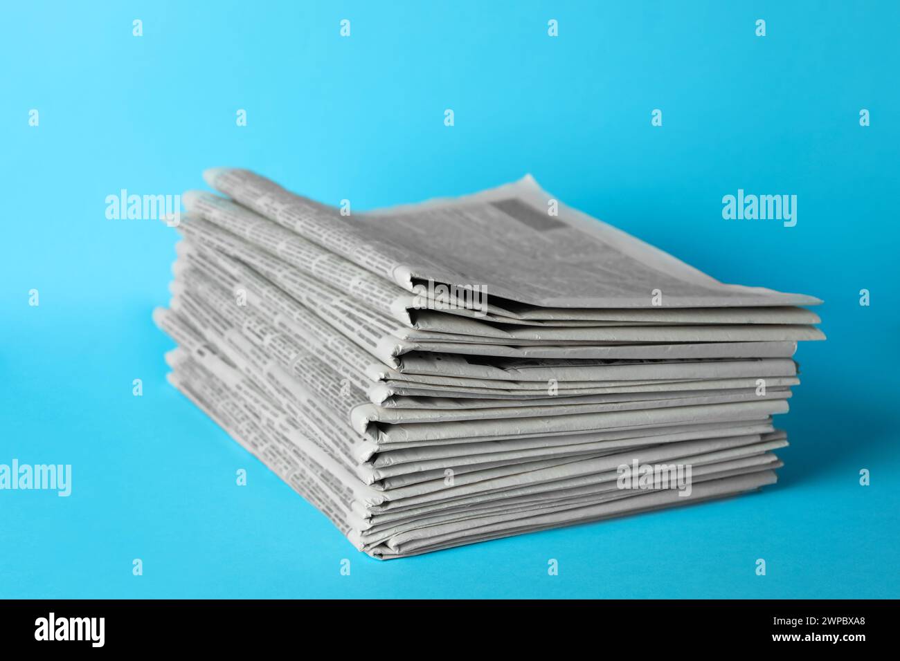 Stack of newspapers on light blue background. Journalist's work Stock Photo