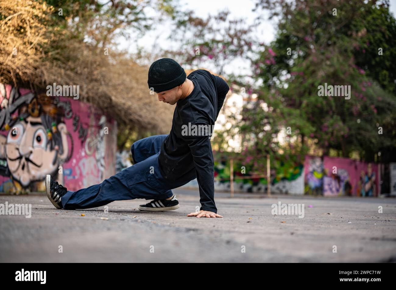 Chiang mai, Thailand - Mar 05 2024: A cool, professional Asian male hiphop breakdancer is stylish clothes and beanie is performing his breakdance on t Stock Photo