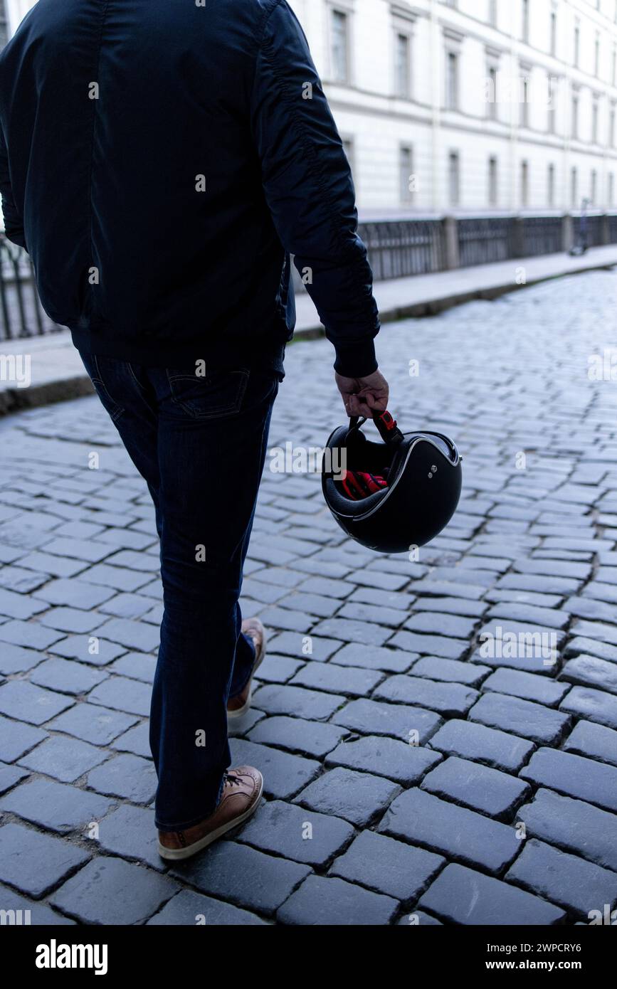 carrying motorcycle helmet man carrying a motorcycle helmet in his hands Stock Photo