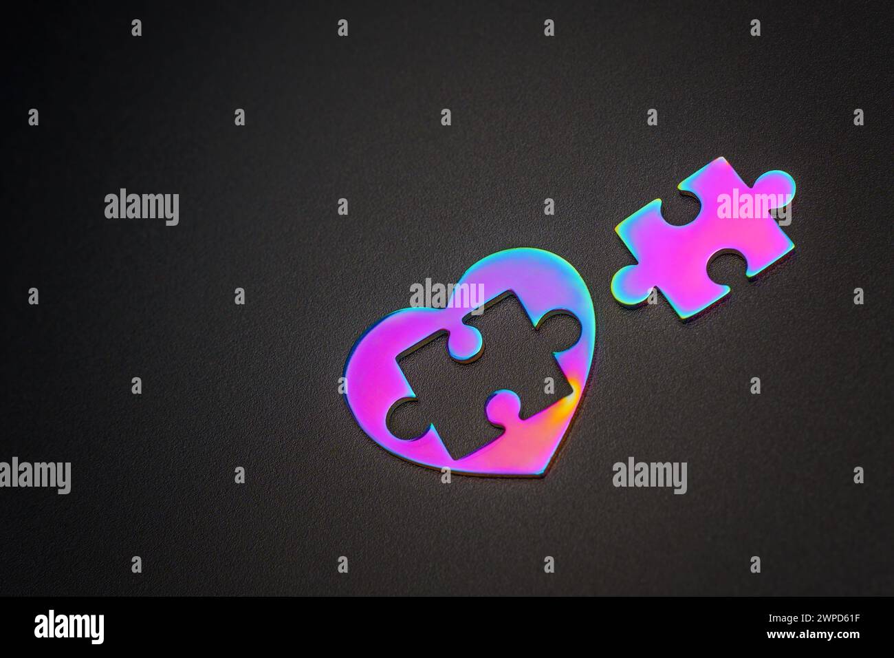 Colorful heart puzzle with an extracted puzzle piece, delicately placed beside it on a black backdrop. Intricacies of relationships and the delicate n Stock Photo