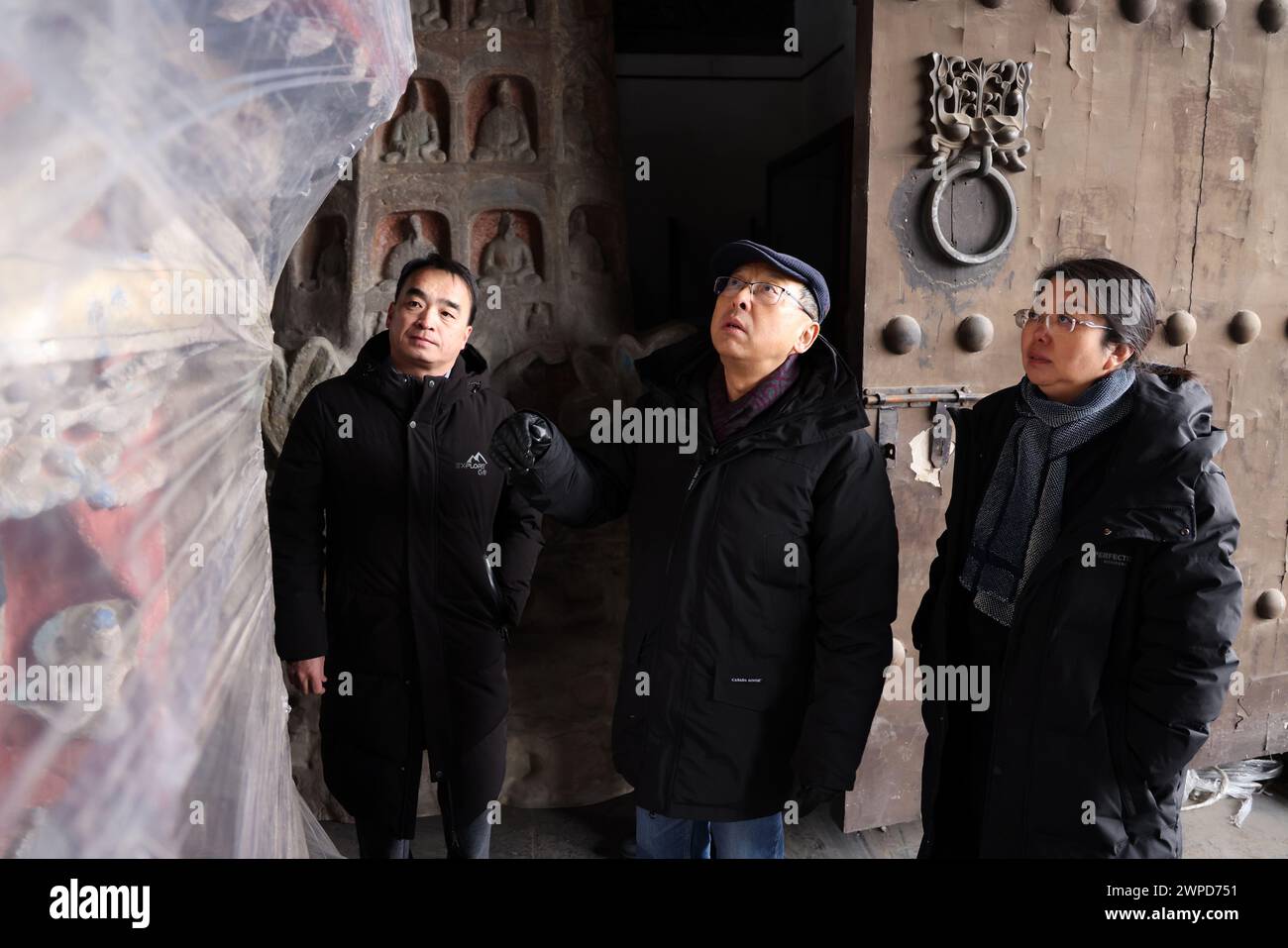 (240307) -- DATONG, March 7, 2024 (Xinhua) -- Hang Kan (C) and his colleagues exchange ideas about the preservation scheme of 3D printed model of Cave No. 12 of the Yungang Grottoes in Datong, north China's Shanxi Province, Dec. 29, 2023. Hang Kan is head of the research institute of the Yungang Grottoes, a UNESCO World Heritage site featuring over 50,000 stone Buddhist sculptures. Yungang Grottoes was built during the Northern Wei Dynasty (386-534). It is considered a pinnacle of Chinese Buddhist art and represents the highest level of sculptural artistry in the world during the 5th centu Stock Photo