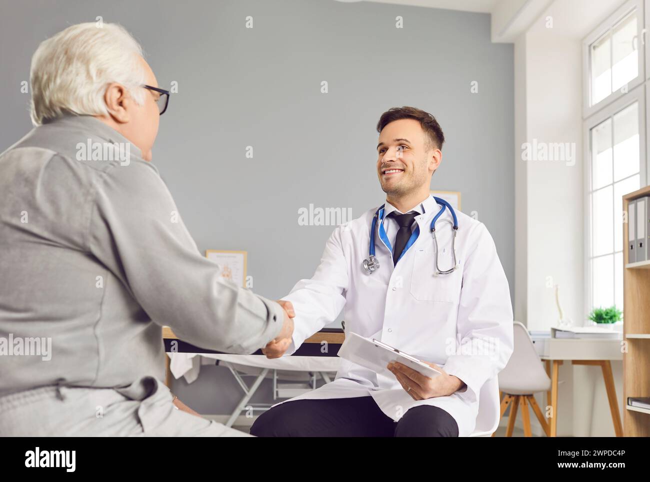 Friendly male doctor therapist shaking hands with elderly senior man ...