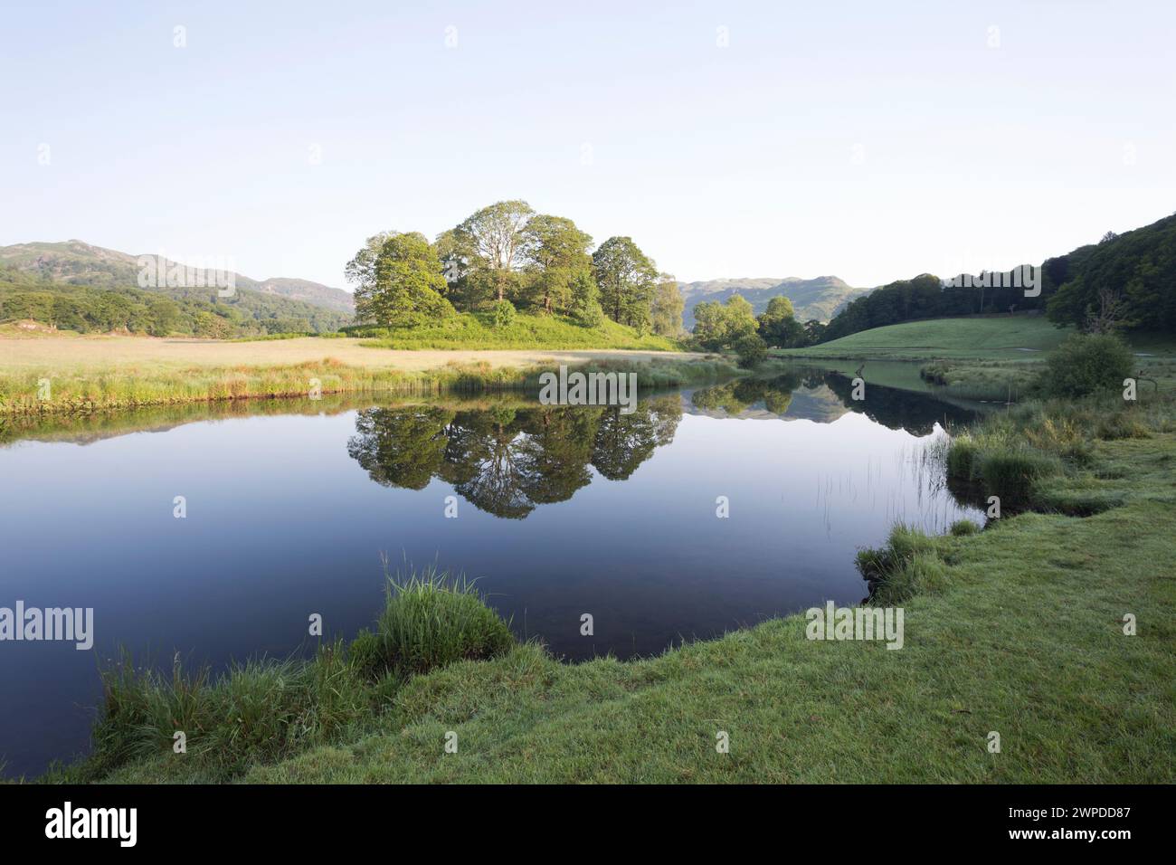 UK, Cumbria, Lake District, the Langdale pikes at dawn reflected in Elterwater. Stock Photo