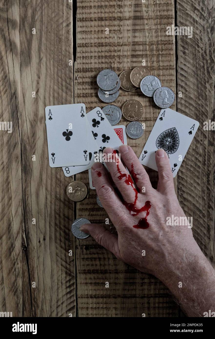 Dead mans hand playing cards aces and eights on wooded background. with Blood stained hand. Stock Photo