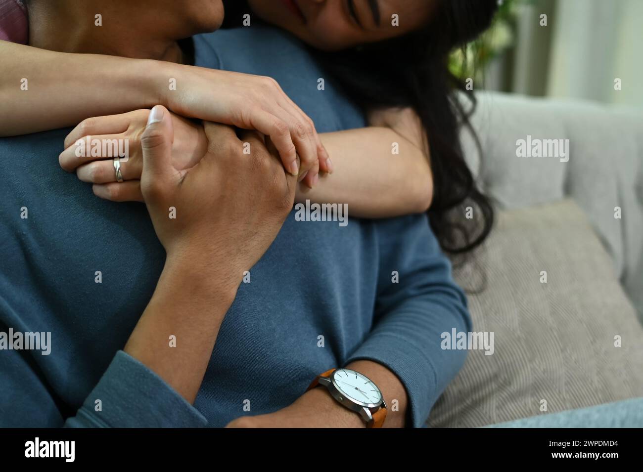 Cropped shot loving woman hugging her husband on couch from behind ...