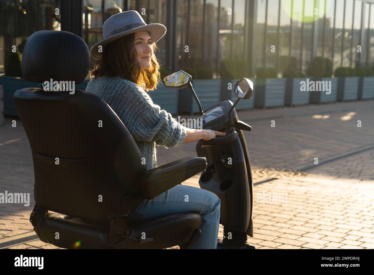 Woman tourist riding a four wheel mobility electric scooter on a city street.. Stock Photo