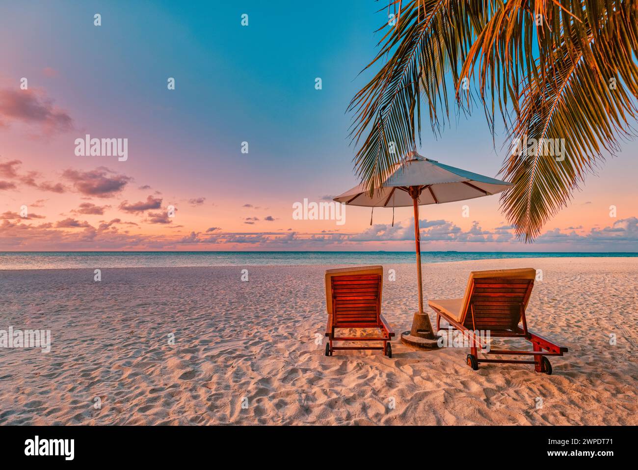 Amazing sunset beach. Romantic couple chairs umbrella. Tranquil togetherness love concept scenery, relax beach, beautiful landscape design. Getaway Stock Photo