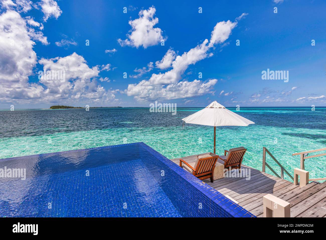 Luxury beach resort, bungalow near endless pool over beautiful blue sea. Amazing tropical island, summer vacation concept. Couple chairs with umbrella Stock Photo