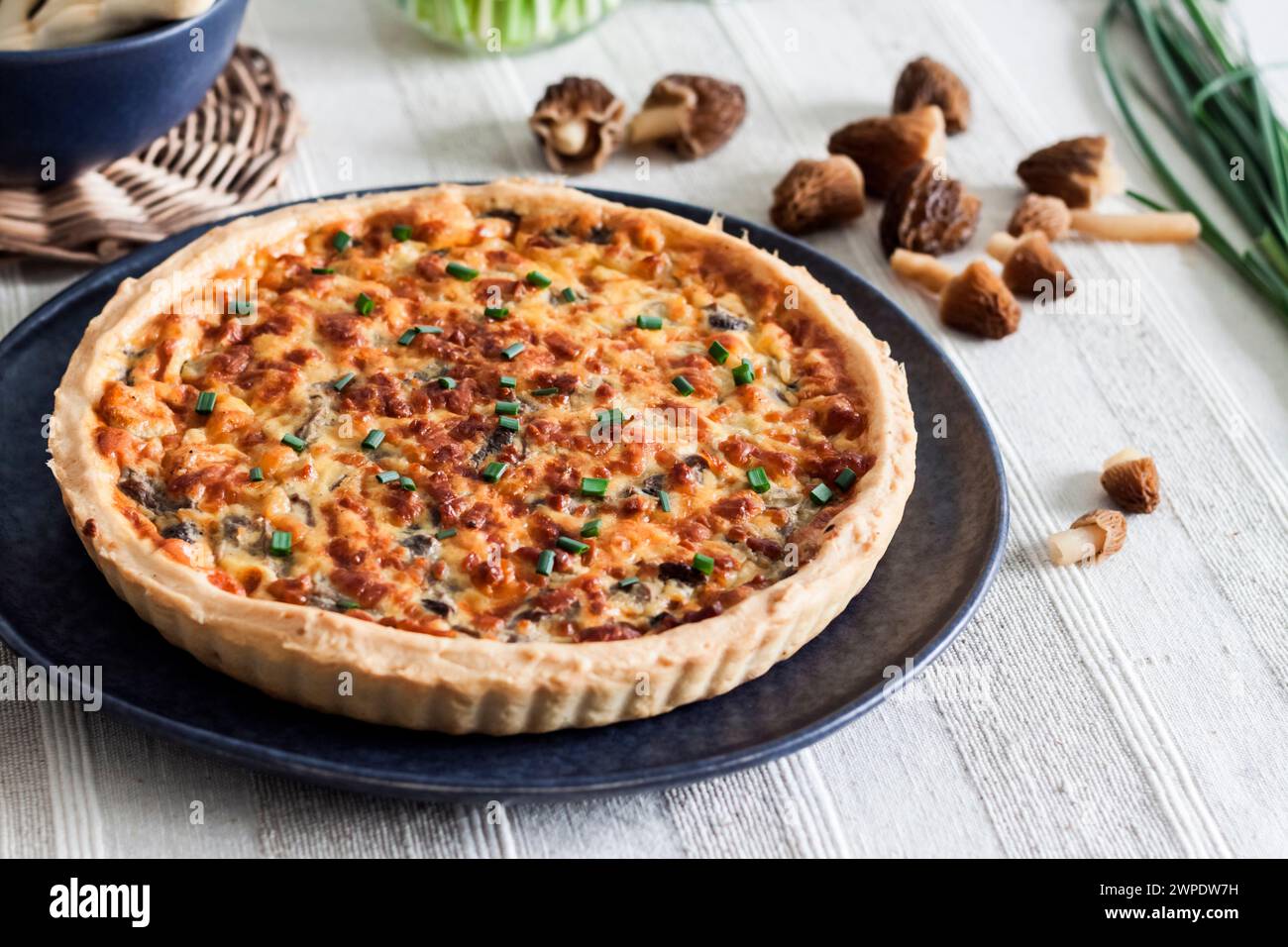 Quiche - open tart pie with morel mushrooms, onion and cheese on a plate Stock Photo