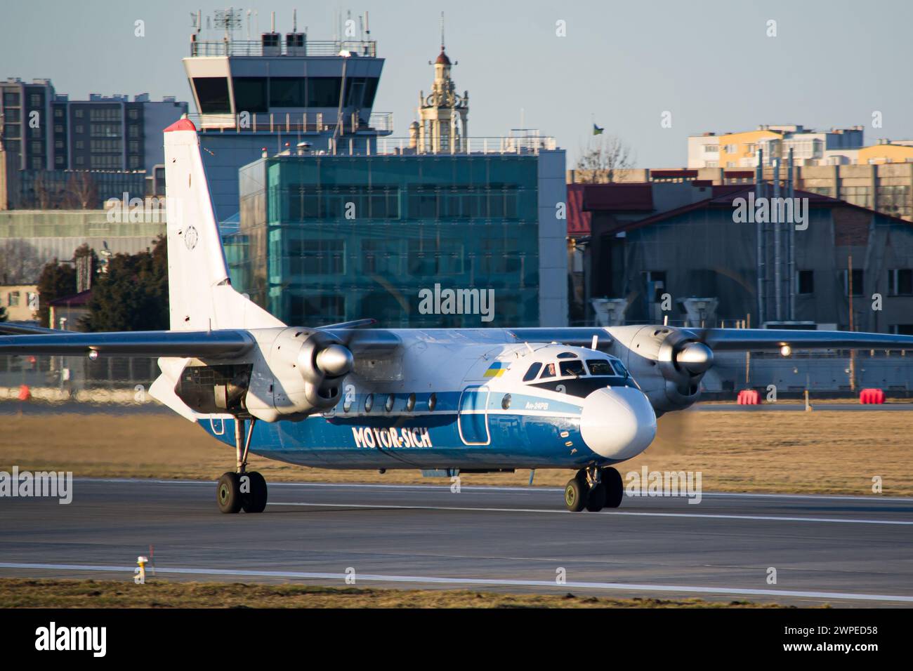 Ukrainian airline's Motor Sich Antonov An-24RV regional aircraft taxiing for takeoff at Lviv Airport during golden hour Stock Photo