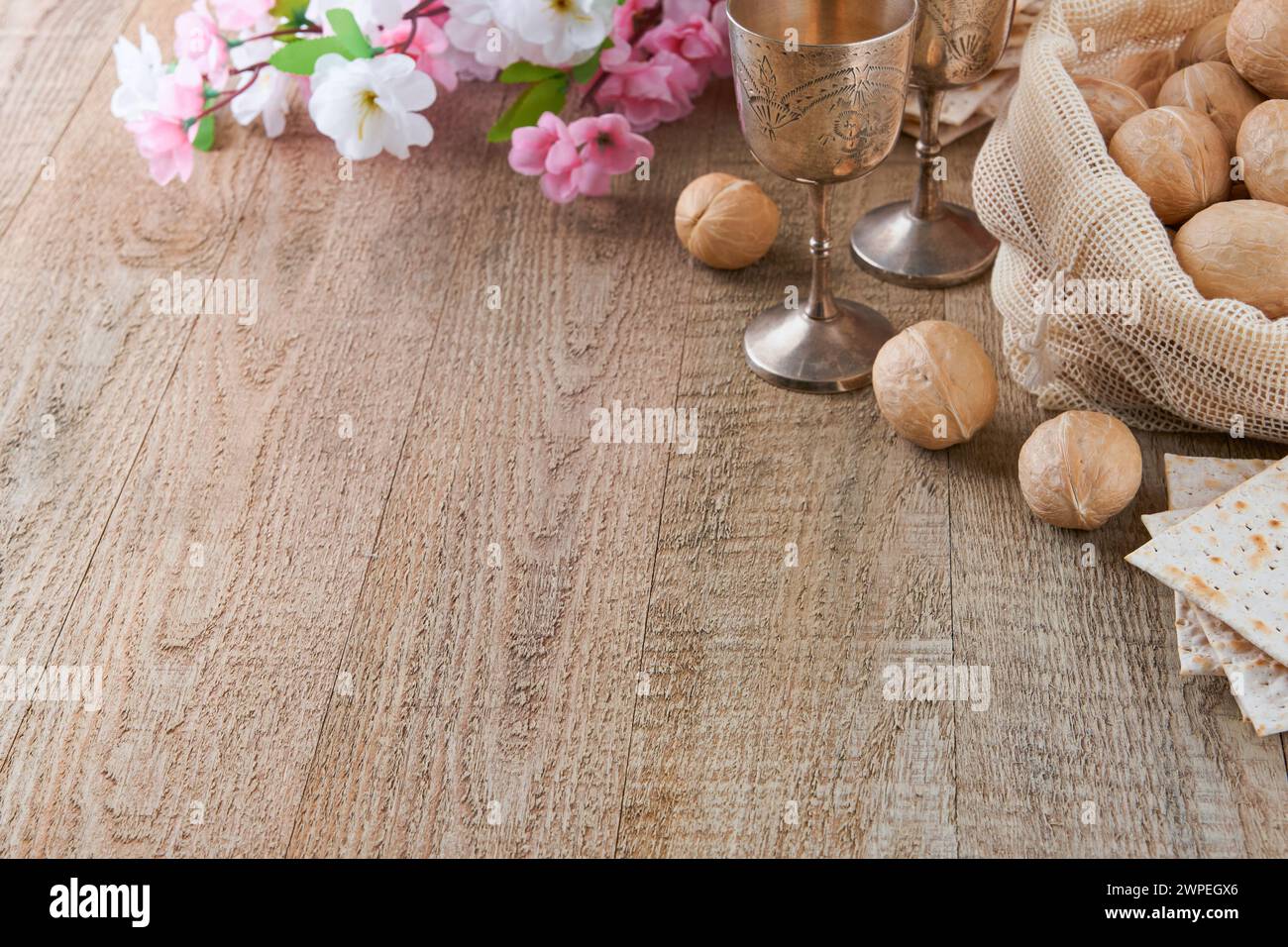 Passover celebration concept. Matzah, red kosher and walnut on wooden vintage table table in front of spring blossom tree garden and flowers landscape Stock Photo