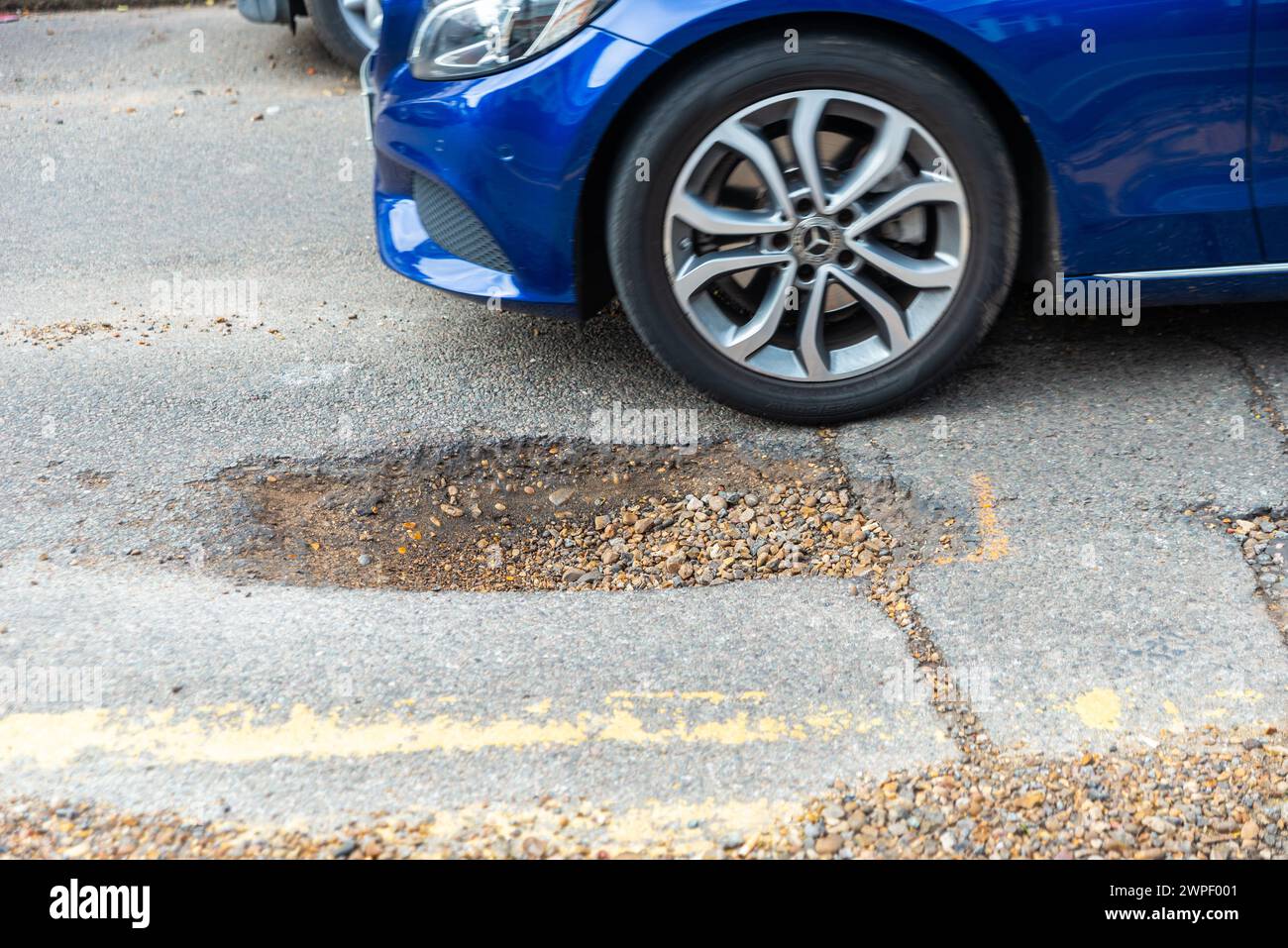 Large pothole in a road in Westcliff on Sea, Southend, Essex, UK, in need of repair. Car passing pot hole Stock Photo