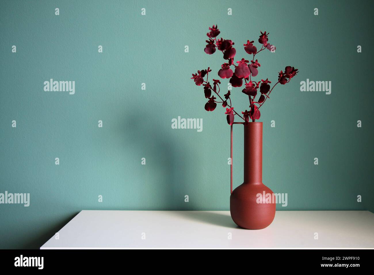 Blooming branch in a modern ceramic vase on a white table. Oriental style desiogn. Space for your text. Stock Photo