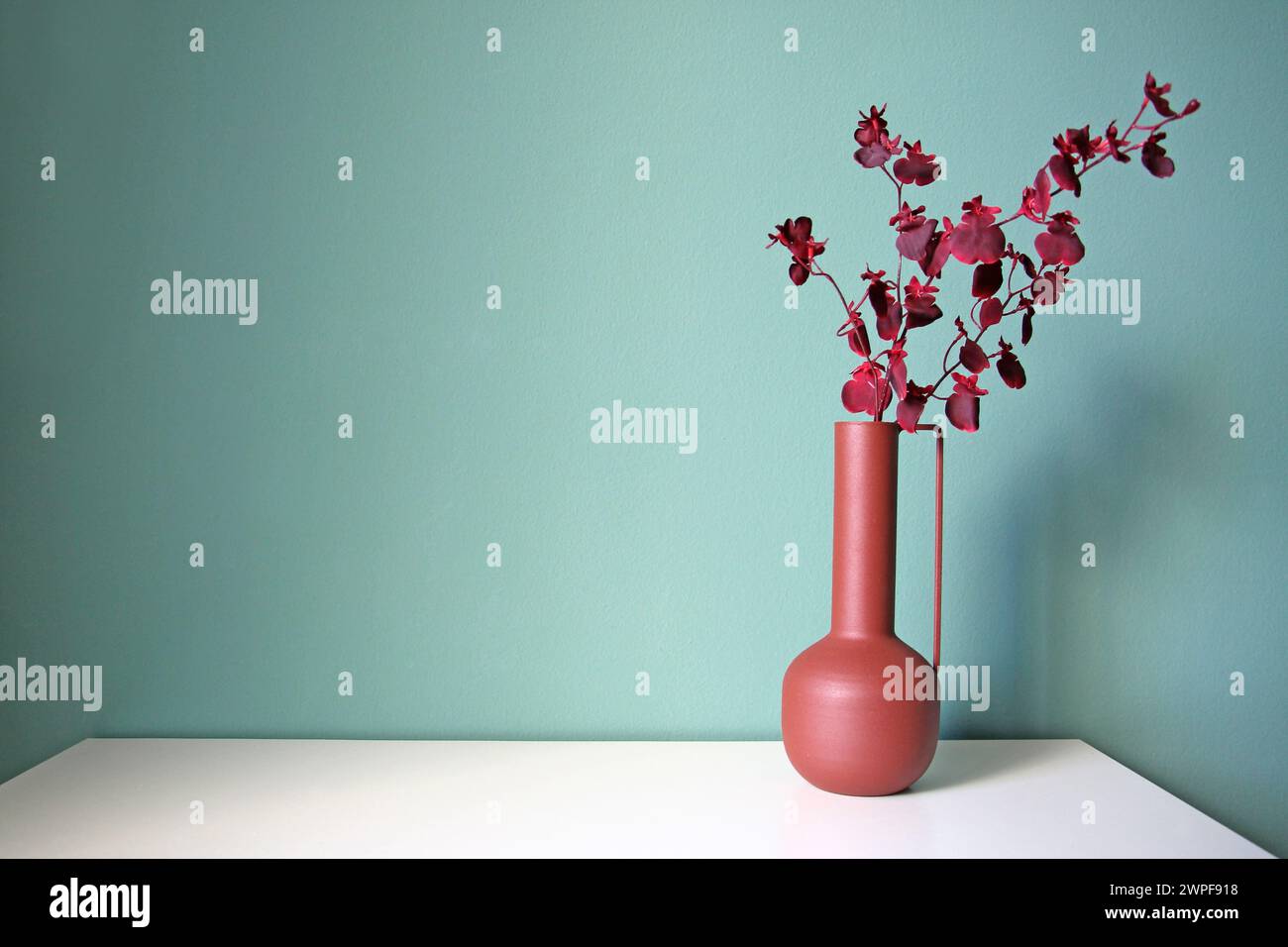 Blooming branch in a modern ceramic vase on a white table. Oriental style desiogn. Space for your text. Stock Photo