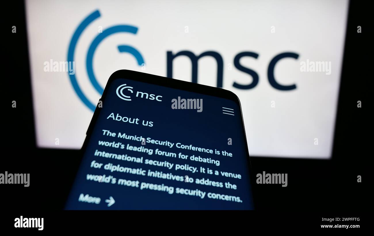 Mobile phone with website of annual event Munich Security Conference (MSC) in front of logo. Focus on top-left of phone display. Stock Photo