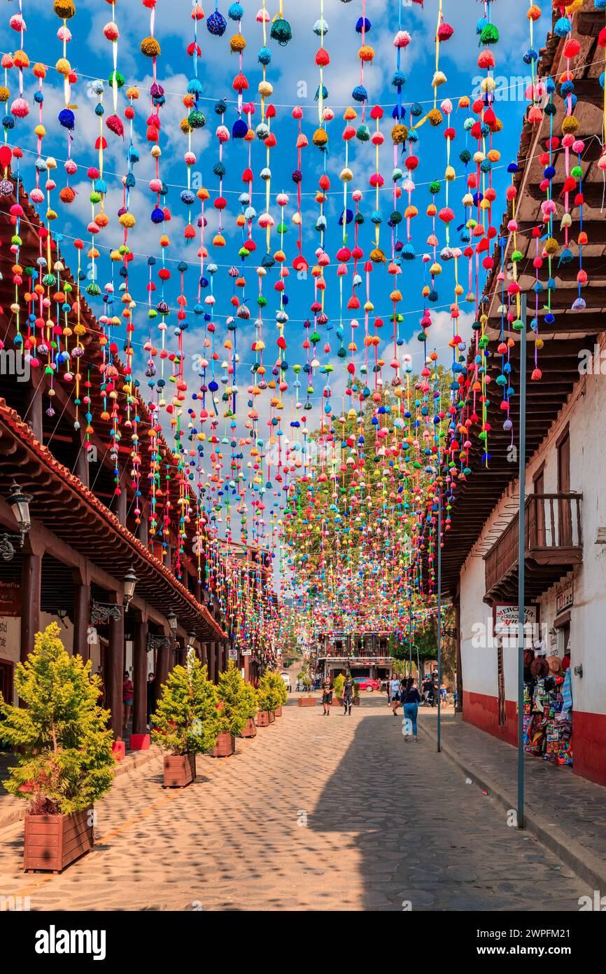 Vibrant hanging decorations in a cobblestone alleyway Stock Photo
