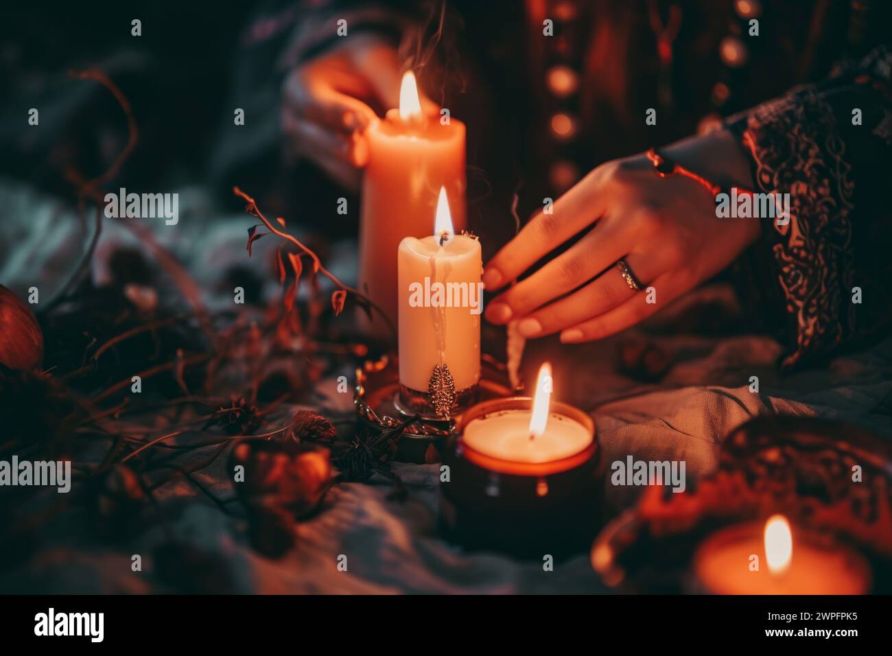 Unrecognizable female woman witch lighting different burn candles flame making rite herbs mystic magic ritual magical attributes indoor night evening Stock Photo