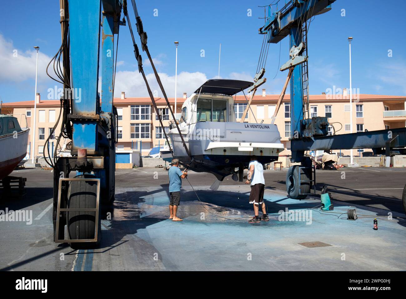 cleaning the underside of a boat on a boat lift in the marina harbour Corralejo, fuerteventura, Canary Islands, spain Stock Photo