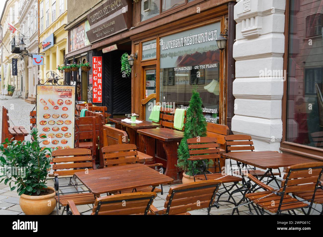Bratislava, Slovakia Outdoor seating area with wooden chairs and tables with food menu chart display outside a Slovak restaurant. Stock Photo