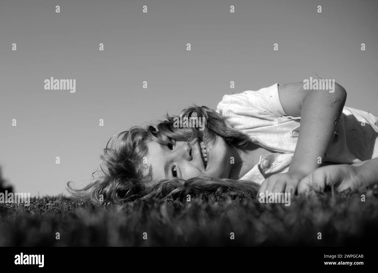 Portrait of a happy smiling child boy playing on grass field outdoor. Laughing child. Expressive facial expressions. Stock Photo