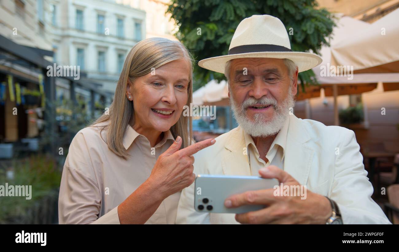 Happy grandparents blogging. Close up elderly couple retired family Caucasian woman man talk stream using gadget mobile phone talking travelling Stock Photo