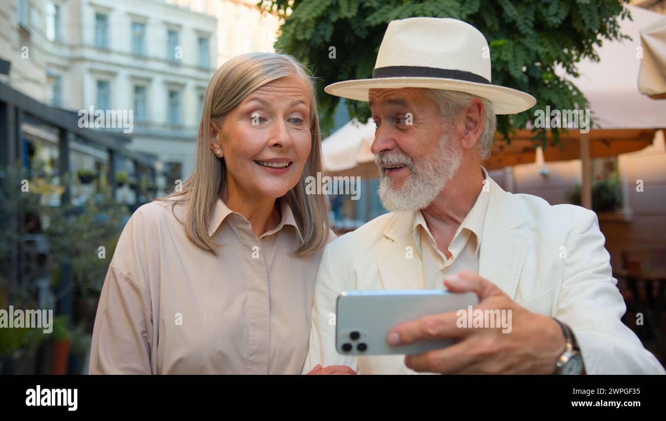 Happy grandparents blogging. Close up elderly couple retired family Caucasian woman man talk stream using gadget mobile phone talking travelling Stock Photo