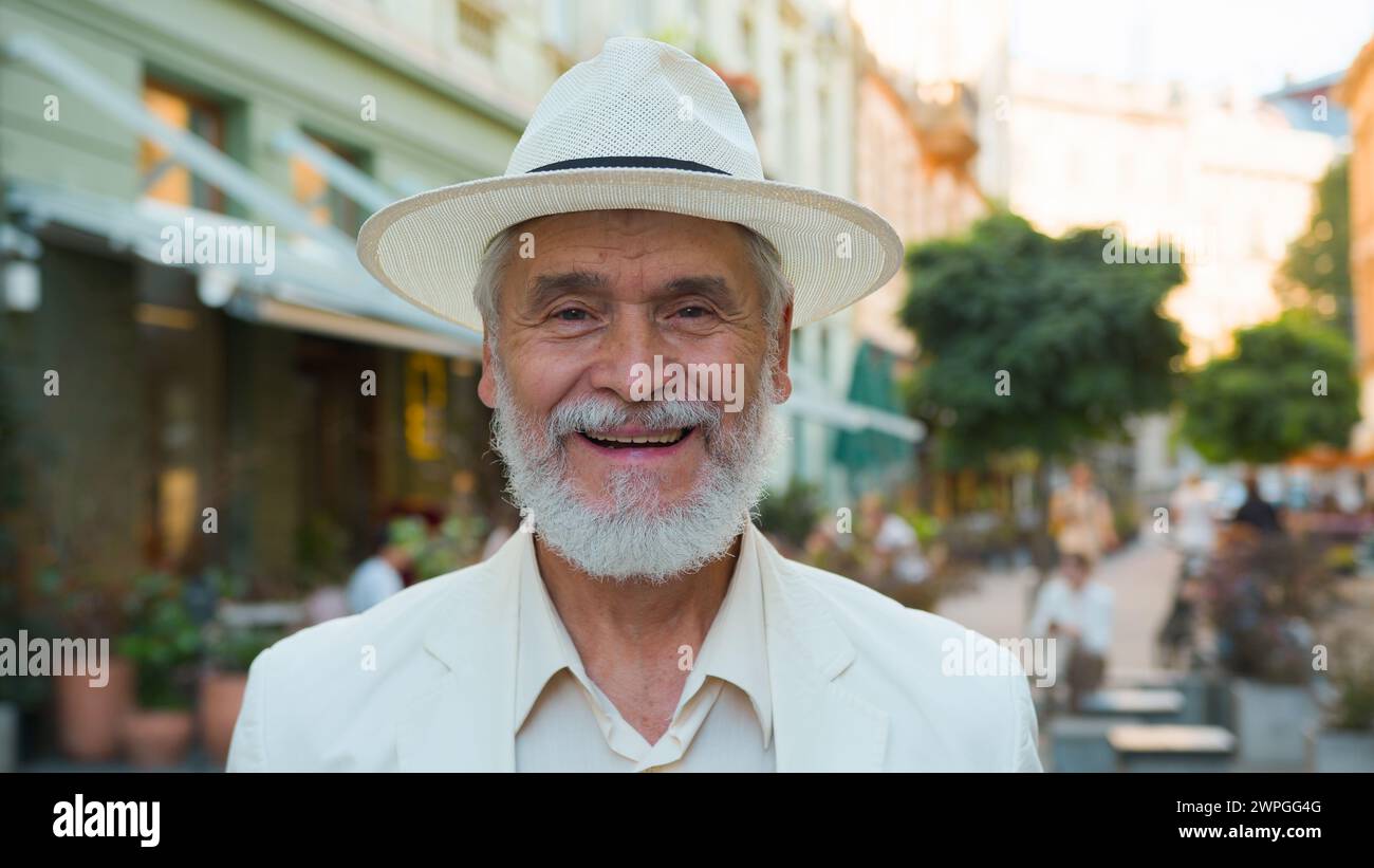 Smiling happy laughing old senior guy elderly mature grey-haired Caucasian elegant businessman male man tourist traveler looking at camera positive Stock Photo