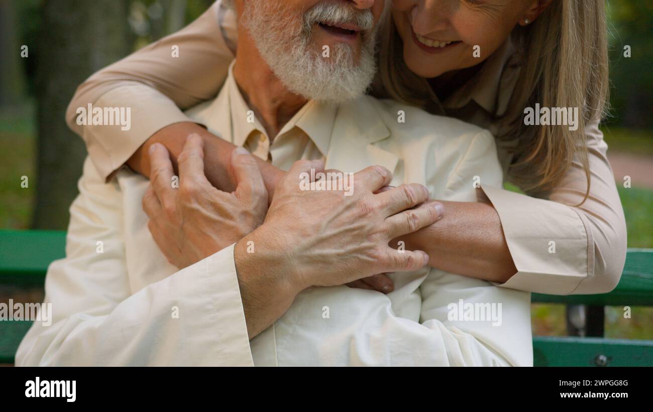 Close up cute mature elderly married Caucasian couple woman embracing hugging man retired happy family holding hands smiling loving husband wife Stock Photo