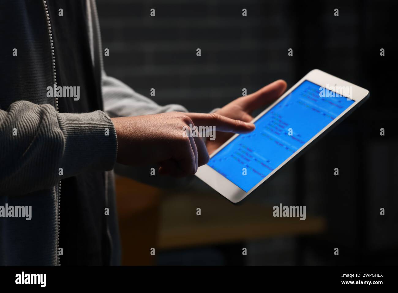 Hacker using tablet computer in dark room, closeup Stock Photo