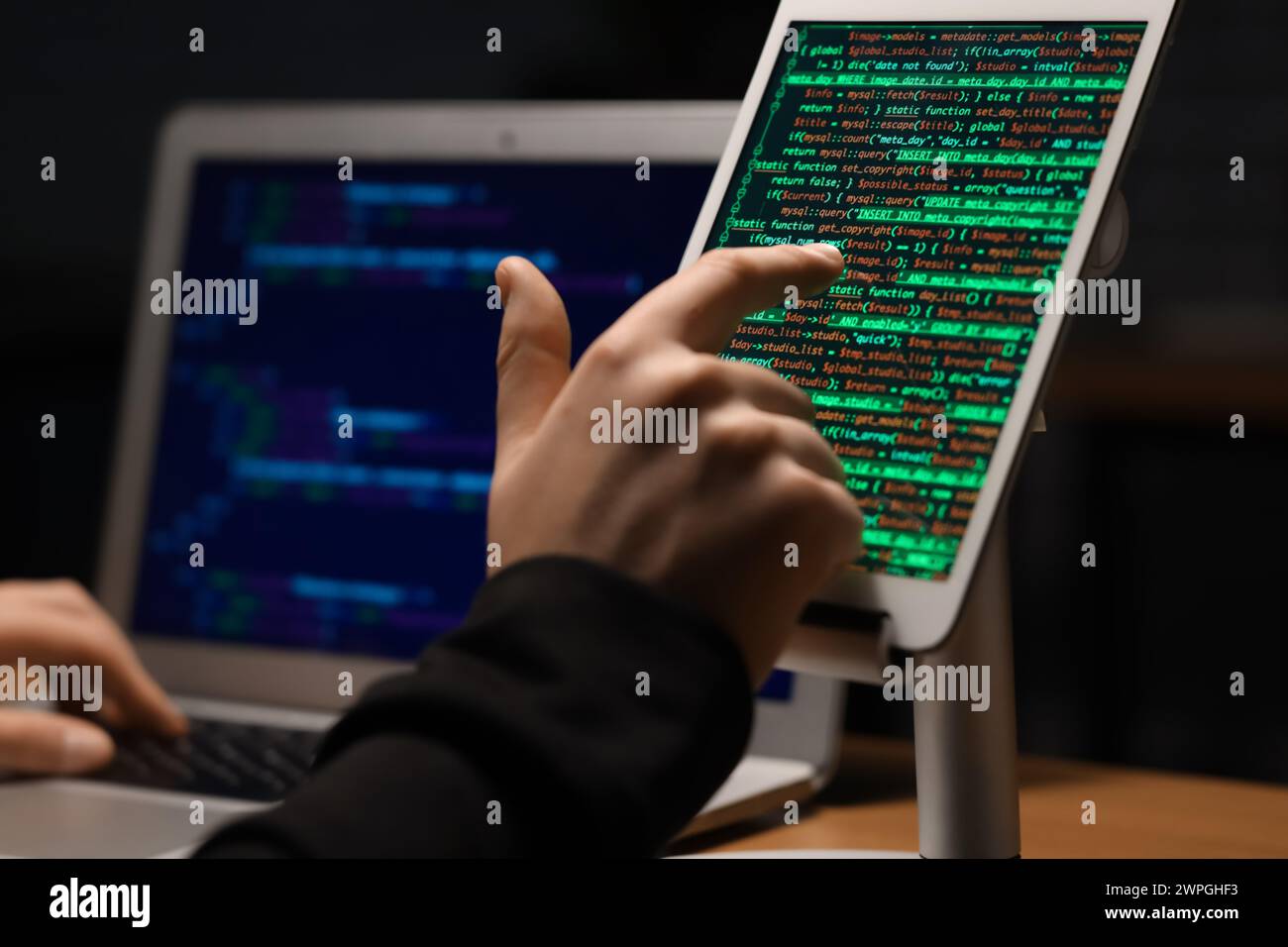 Hacker using tablet computer in dark room, closeup Stock Photo
