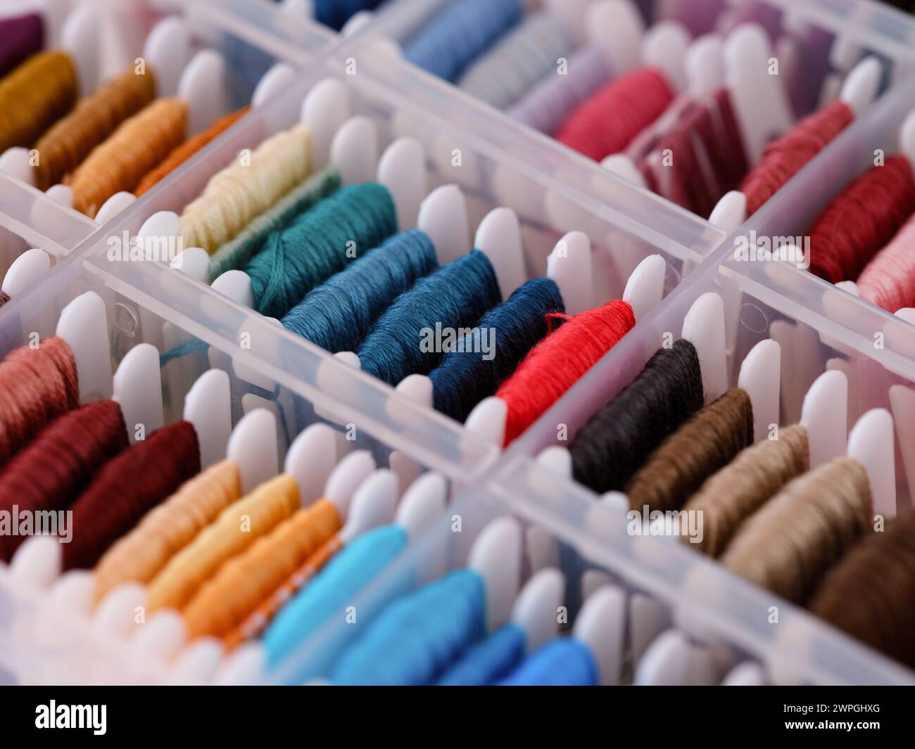 Bobbins with different colour embroidery threads in a plastic sorting box. Close-up Stock Photo
